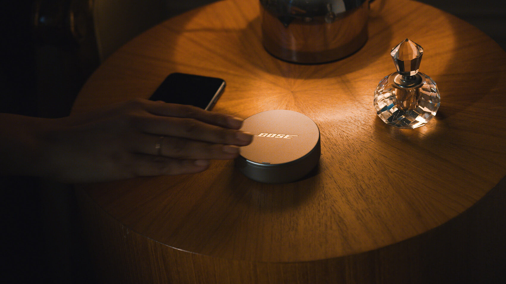 Close up of a hand reaching for a Bose Sleepbuds container on a bedside table at night in a branded content film