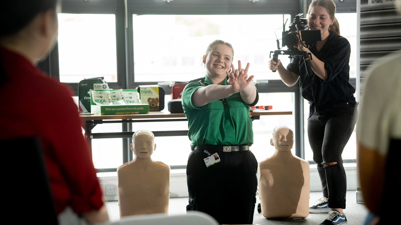 A St John Ambulance volunteer demonstrating first aid techniques while being filmed by a Rise Media camerawoman