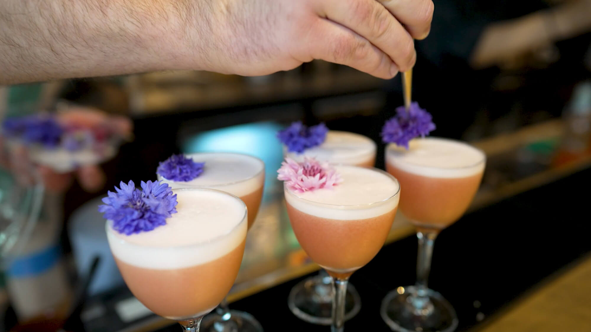 Close up of cocktails being mixed and topped with a flower garnish at a Hearst Live and Volvo sponsored event filmed by Rise Media