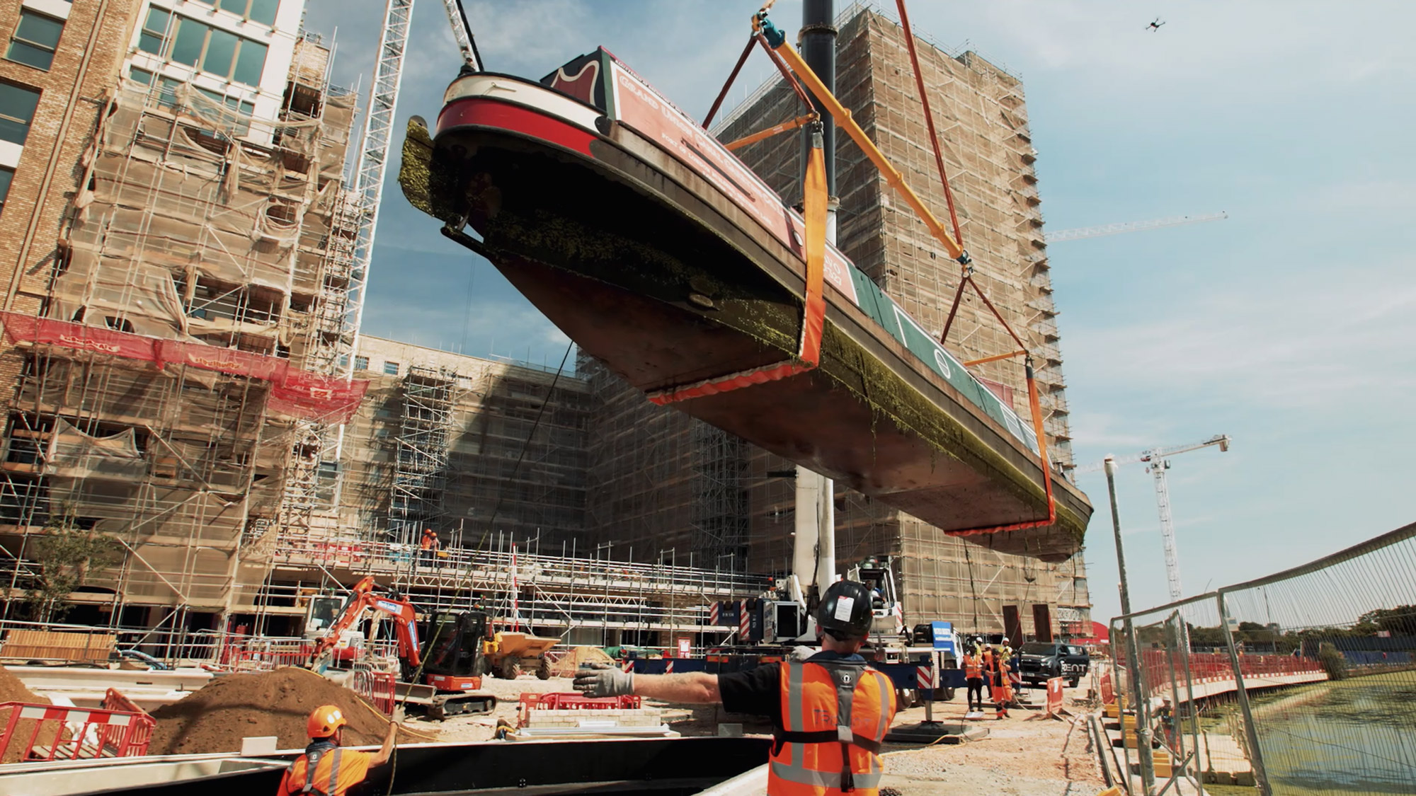 A still image from a Rise Media video of a narrowboat being lifted by crane into a canal