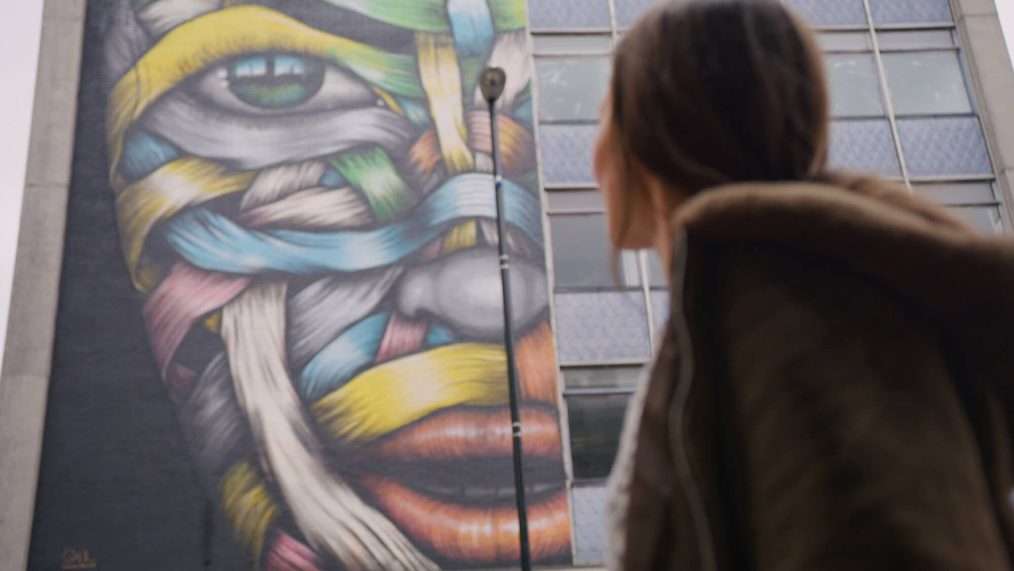 A woman looks at a large colourful mural in the street in our Spaces Property Showreel, from the Rise Media case studies archive