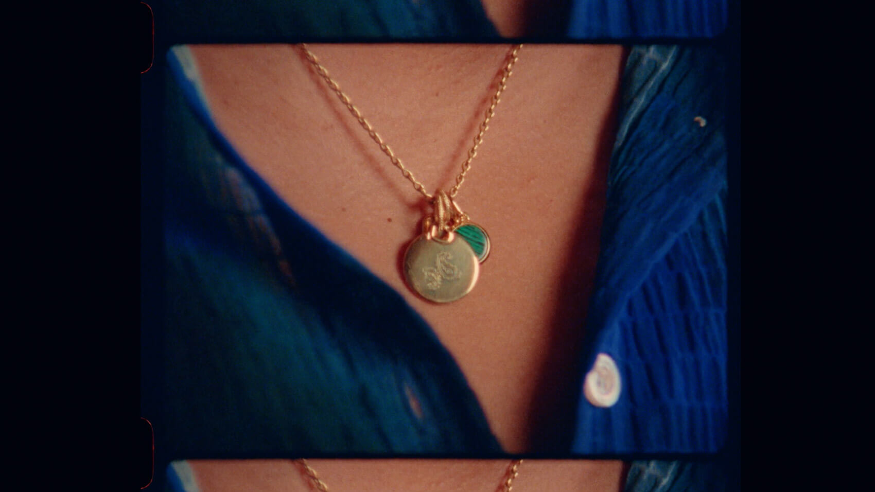A close up of a necklace on a model wearing a blue shirt
