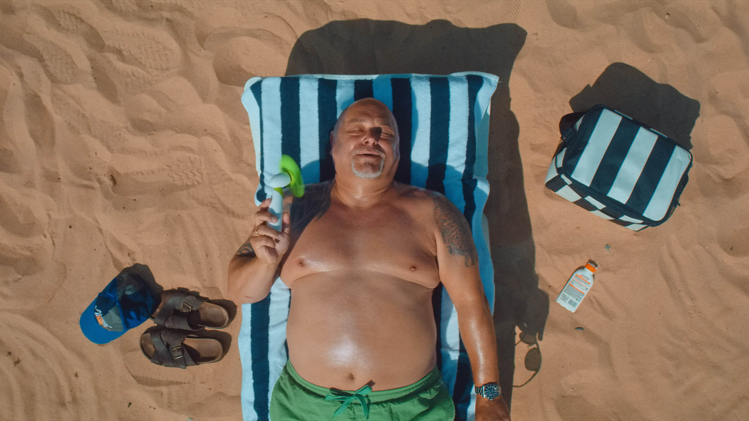 A still of a sunbathing man from our Hoo video shot on Great Yarmouth beach, from the Rise Media case studies archive