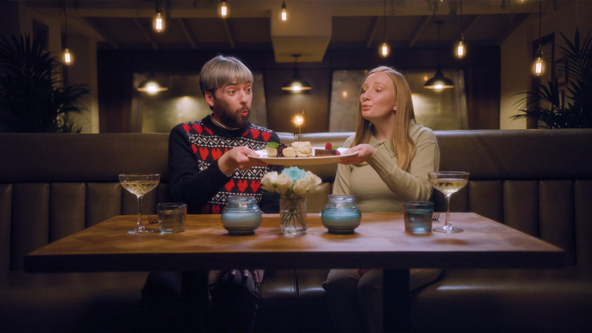 A male and female couple in a restaurant on Valentine's Day blowing out a sparkler on top of a dessert plate in a Buy A Gift ad, from the Rise Media case studies archive